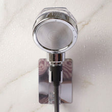 The chrome shower spray head is mounted on a wall bracket, with water droplets visible on the white marble surface.