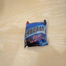 A blue and black plastic bag of toilet cleaner tablets with Chinese text rests on a light wooden surface.