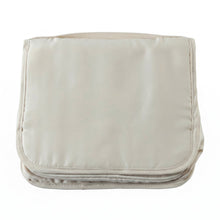 A neatly folded rectangular beige toiletry bag with a handle on a plain white background.