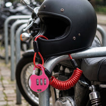 A black motorcycle helmet is secured to a bike rack with a pink combination lock and red coiled cable, with a 