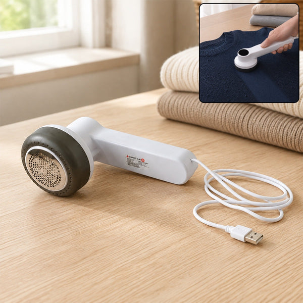 White and dark grey fabric lint remover with a USB cable on a wooden table, with an inset showing it in use on a navy