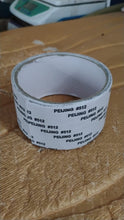 A roll of grey mesh repair tape with white backing, sitting on a textured brown surface.