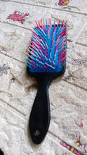 Packaging for the ergonomic hair brush alongside the product, ready for use.