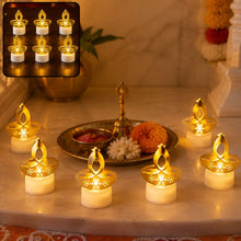 Six golden LED diya tealight candles arranged on a white marble surface with a brass tray and flowers.