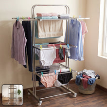 A stainless steel 3-layer clothes drying rack with various clothing items, including shirts, towels, and underwear.