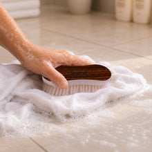 Cleaning cloth being scrubbed with ergonomic laundry brush in hand