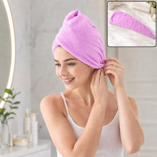 A smiling woman in a white tank top wears a purple microfiber hair wrap, securing it above her ear. 