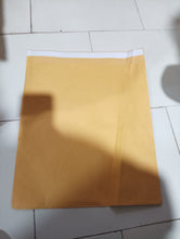 A single brown kraft envelope with a white self-seal strip, lying flat on a tiled floor.