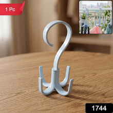 A light blue plastic rotating multi-hook hanger sits on a wooden table, with a red 