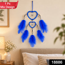 A blue heart-shaped dream catcher with feathers and silver beads hangs on a light wall, with a red banner saying 