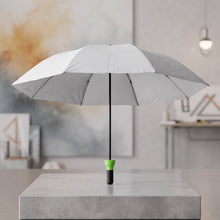 Open grey umbrella with a black shaft and bright green handle standing upright on a concrete block.