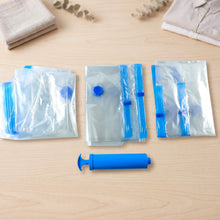 Three clear vacuum storage bags with blue accents and a blue hand pump are laid out on a light wooden surface.